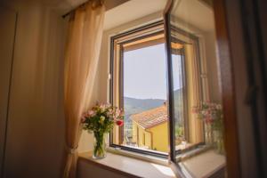 a window with a vase of flowers on a window sill at Tosco Suite "Ecclesia" in Sasso dʼOmbrone