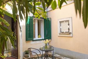 a table with chairs and a window with green shutters at Lemon apartment Piran in Piran