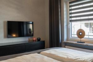 a bedroom with a tv and a bed and a window at Apartment MeerZeit in Büsum