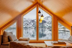 a room with a large window with snow covered mountains at Fjordview Ryten 2 Retreat in Sund