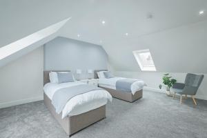 a bedroom with two beds and a chair at Connel House - Luxury self-catering 4-bedroom home in Connel
