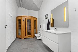 a bathroom with a toilet and a wooden cabinet at BV155-Blavand-Gronnevaenget-1-D in Blåvand +13 photos