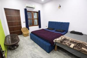 a bedroom with a blue bed and a table at Vrinda vas Homestay in Mathura +30 photos