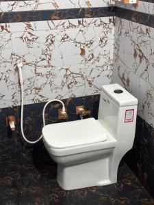 a white toilet in a bathroom with a hose at Vrinda vas Homestay in Mathura