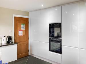 a kitchen with white cabinets and a black oven at Stroma in Edderton +16 photos