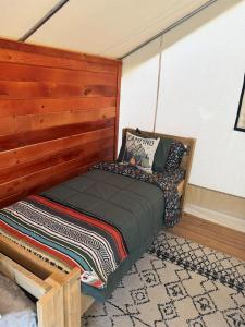 a bed in a room with a wooden headboard at Peaceful Glamping Retreat at Roaring River in Cassville