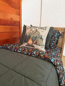 a bed with a pillow with a fire on it at Peaceful Glamping Retreat at Roaring River in Cassville