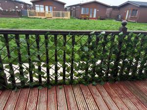 a black fence on a deck with a yard at Blackamores chalet in Mablethorpe
