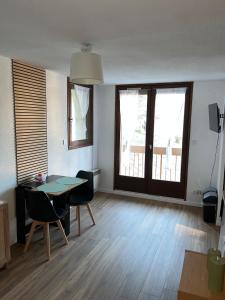a living room with a table and chairs and windows at EcrAin Montagnard in Lélex