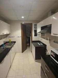 a kitchen with white cabinets and black counter tops at Muscat Beach Hostel in Muscat