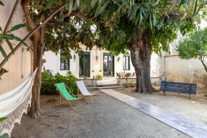 a patio with two chairs and a bench under a tree at Hotel Vella Nit in Canet de Mar