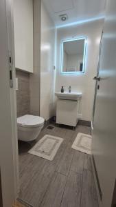 a white bathroom with a toilet and a sink at Urban studio in Bežanija +18 photos
