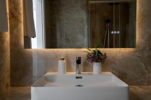 a bathroom sink with a vase of flowers and a mirror at Casa Angelica in Patitiri +13 photos
