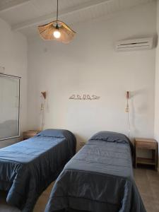 a room with two beds and a light fixture at Casita Cómoda y Acogedora in Trenque Lauquen