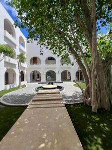 a courtyard of a building with a fountain and trees at New Hotel Serenata Santa Lucia Mérida in Mérida