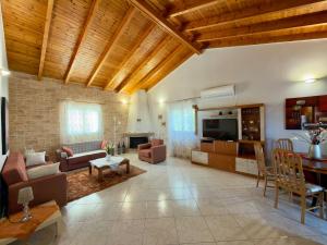 a large living room with a couch and a tv at Villa Erato Keratea in Keratea