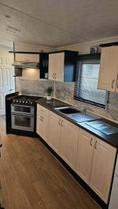 a kitchen with white cabinets and a stove at 16 farmfield in Skipsea +10 photos