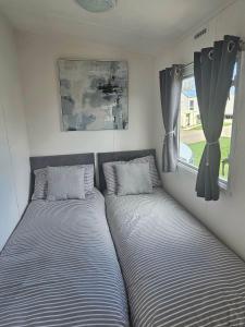 two beds in a small room with a window at 16 farmfield in Skipsea
