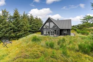 a black house sitting on top of a grassy hill at BV374-Blavand-Krogsande-22 in Blåvand