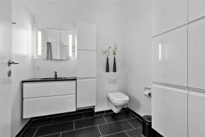 a white bathroom with a toilet and a sink at BV144-Blavand-Horntoftvej-13 in Blåvand +29 photos