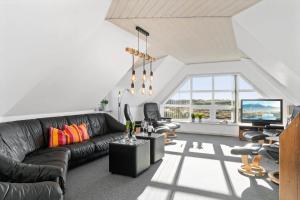 a living room with a black couch and a tv at BV277-Blavand-Klitvej-4 in Blåvand