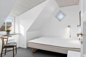 a white bedroom with a bed and a chair at BV277-Blavand-Klitvej-4 in Blåvand +28 photos