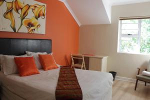 een slaapkamer met een bed met een oranje muur bij Milas Place in Somerset West