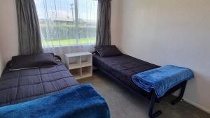 a room with two beds and a window at Hooked On Tiki in Coromandel Town