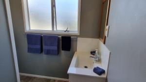 a bathroom with a sink and a window and towels at Hooked On Tiki in Coromandel Town +10 photos