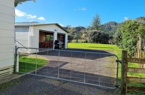 a fence in front of a house with a yard at Hooked On Tiki in Coromandel Town
