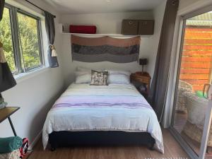 a bedroom with a bed in a tiny house at Beach Bach Whangaumu Bay Tutukaka in Tutukaka