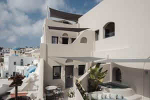 a white building with a balcony with tables and chairs at Galaria Serenity Suites in Vóthon