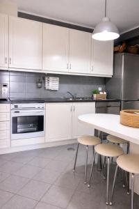 a kitchen with white cabinets and a table with stools at Mindelo apart in front of the best beach of North Portugal in Mindelo