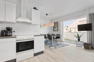 a kitchen with white cabinets and a table with chairs at BV100-Blavand-Blavandvej-53-C in Blåvand +13 photos
