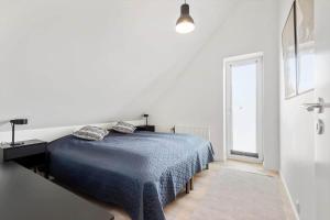 a white bedroom with a blue bed and a window at BV100-Blavand-Blavandvej-53-C in Blåvand