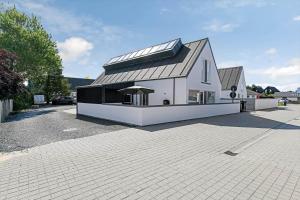 a white house with a silver roof on a driveway at BV100-Blavand-Blavandvej-53-C in Blåvand