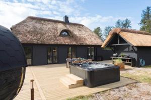 a large deck with a thatched house with a grill at BV264-Blavand-Solhaven-47 in Blåvand