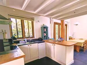 a kitchen with white cabinets and a wooden counter top at Rural Studio with Shared Pool, Large Gardens & Tennis, Dog Friendly! Chichester Holiday Properties in Chichester