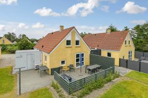 a yellow house with a deck with tables and chairs at BV348-Blavand-Fyrgarden-19 in Blåvand