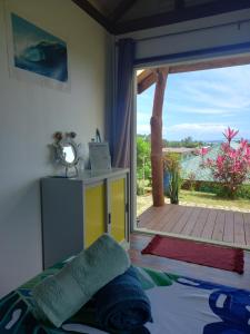 a bedroom with a bed and a large sliding glass door at Fare Te Ava Iti in Teahupoo +4 photos