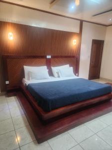 a bedroom with a large bed with a wooden headboard at Ndouha House in Bafoussam