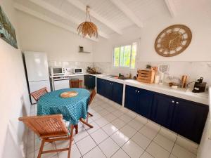 a kitchen with blue cabinets and a table and chairs at Villa Eli -6pers- piscine in Petit-Bourg