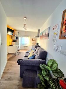 a living room with a blue couch and a kitchen at Acogedor apartamento de 2 habitaciones, parking & conford in El Astillero