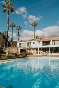 a house with palm trees and a swimming pool at Quinta Clara in Vila Verde