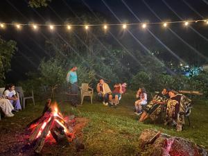 a group of people sitting around a campfire at night at Cabañas AlmA Rural Ibagué in Ibagué