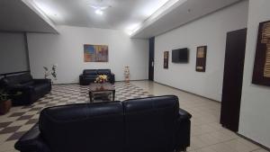 a living room with black leather couches and a table at Flat Olinda 4 Rodas in Olinda