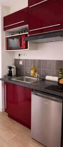 a kitchen with red cabinets and a sink at Perle Dazur Jacuzzi Suite Parking Prive 5min Mer in Menton
