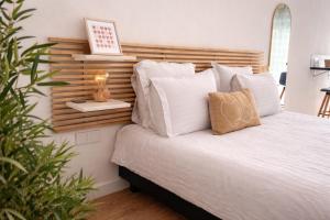 a bed with white pillows and a wooden headboard at Perle Dazur Jacuzzi Suite Parking Prive 5min Mer in Menton