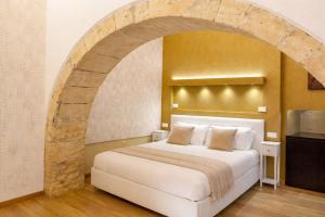 a bedroom with a large white bed with an archway at Martini Castello Boutique Rooms - Historic Center & Cathedral in Cagliari