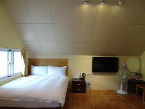 a bedroom with a bed and a flat screen tv at Goose House in Yung-an-ts'un